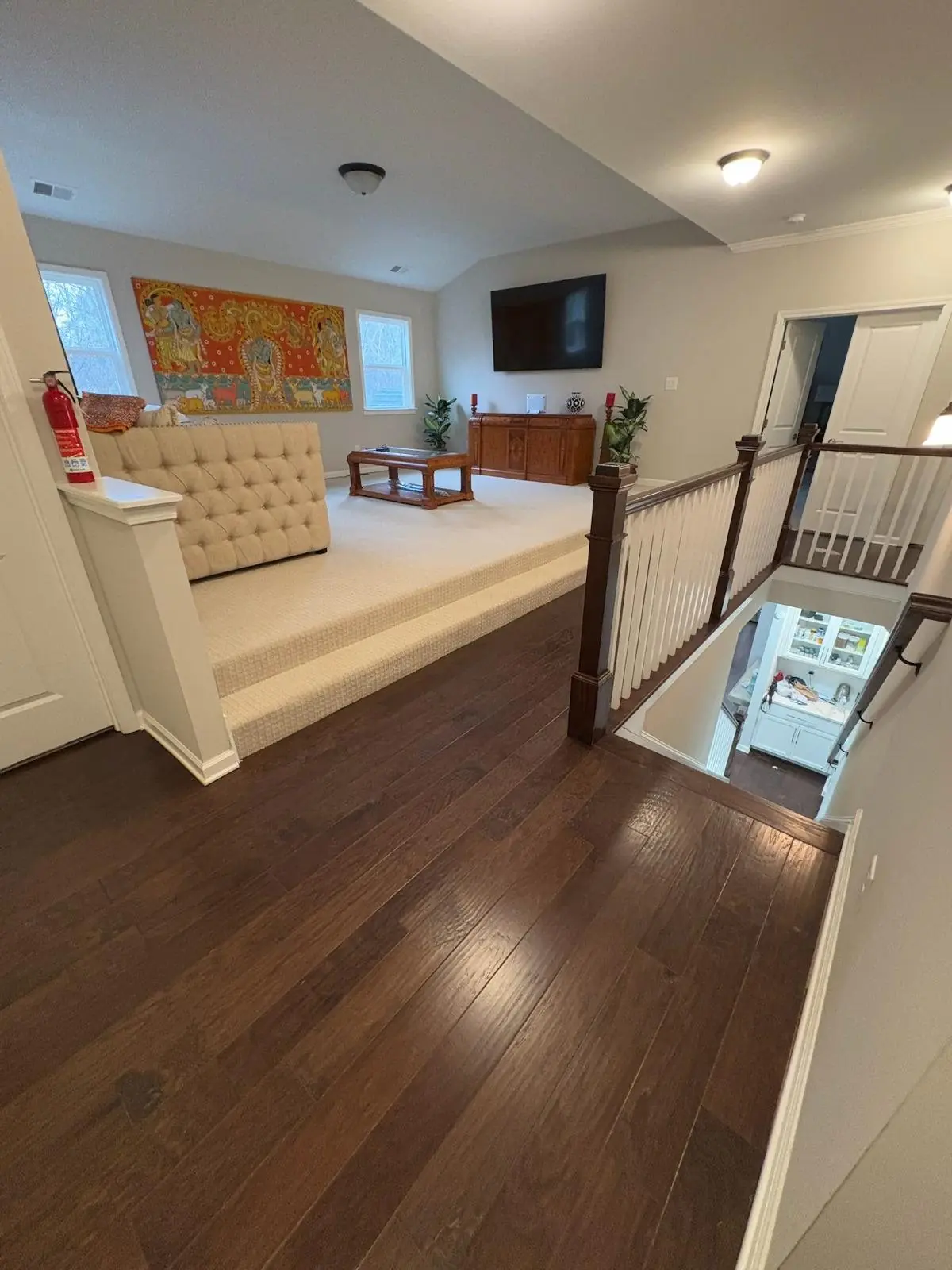 Dark hardwood floor on an upper landing overlooking a living room