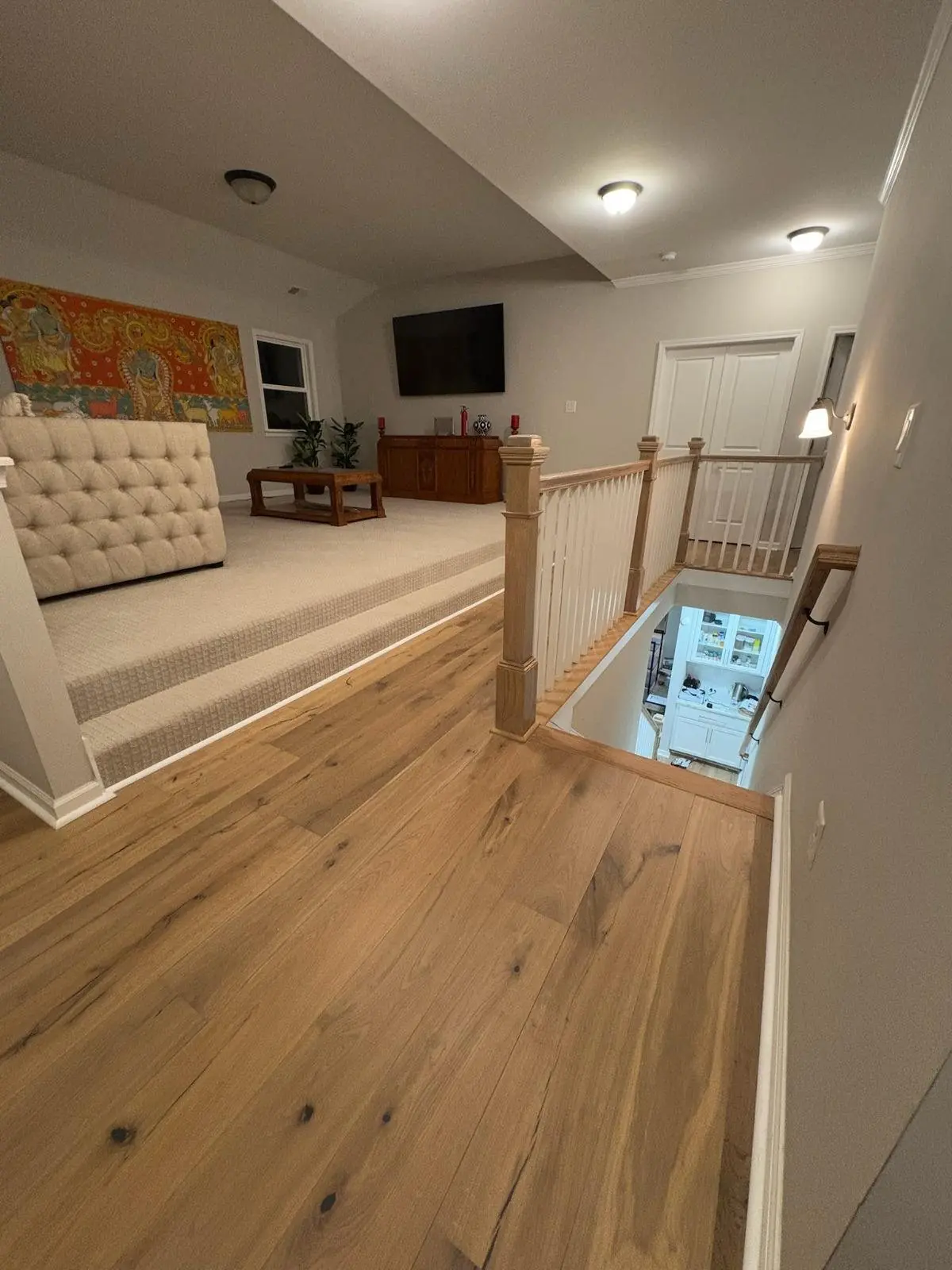 Light oak plank floor on a landing above a carpeted living room