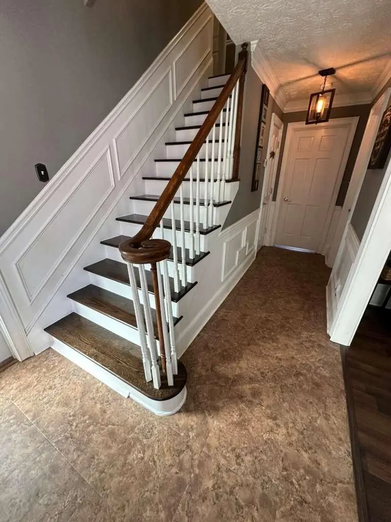 Refinished wood staircase with white balusters and a dark handrail