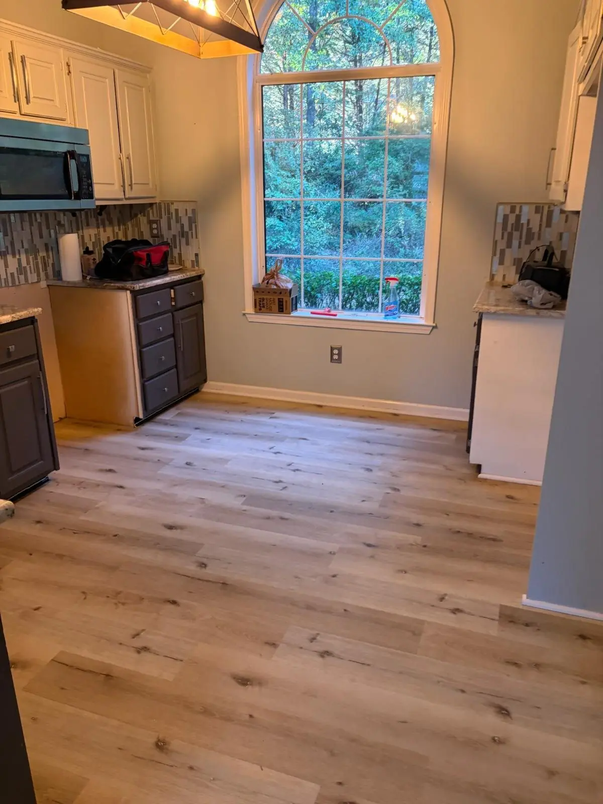 Kitchen with pale wood flooring and dark lower cabinets