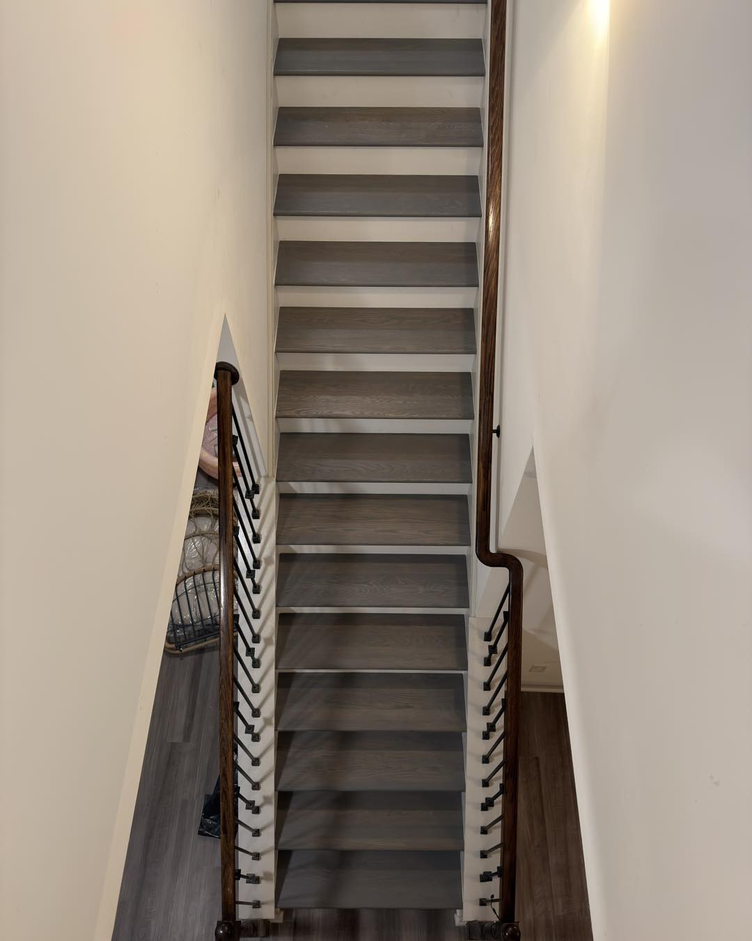 Refinished wood staircase with white balusters and a dark handrail