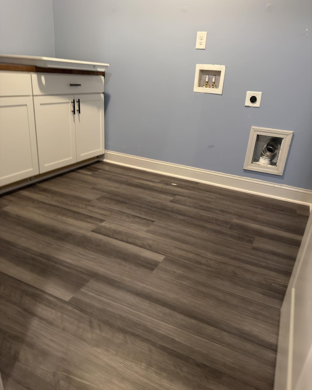 Kitchen with a white island and light wood plank flooring
